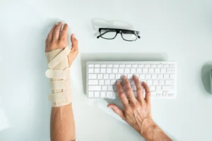 An office employee wearing a wrist brace types up a workers' compensation claim.