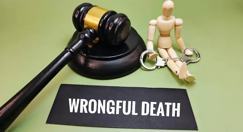 A wooden figure is in handcuffs beside a gavel and wrongful death sign representing criminal negligence and legal liability claims in South Carolina.