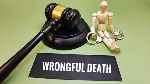 A paper spelling out wrongful death beside a gavel and wooden figure representing a wrongful death lawyer helping a vicitim whose loved experienced a wrongful death.