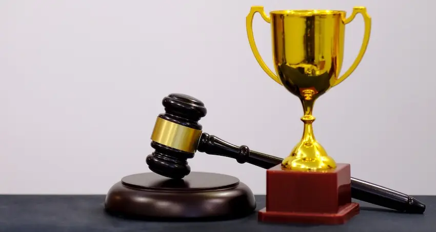 A golden trophy with a legal gavel is symbolizing a successful sports injury attorney case verdict and compensation award in South Carolina at McDougall LawFirm LLC.