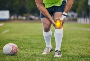 A male athlete is holding his injured knee on the soccer field needing a sports injury attorney for liability claim assistance in South Carolina.